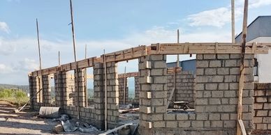 Partially constructed building with concrete block walls under a blue sky.