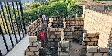 Construction workers building walls with bricks on a sunny day.