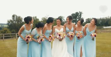 Bride and bridesmaids in light blue dresses outdoors.