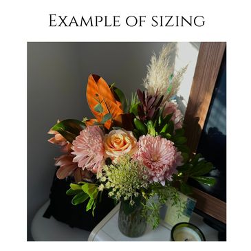 A medium-sized bouquet with flowers and greenery in a glass vase.