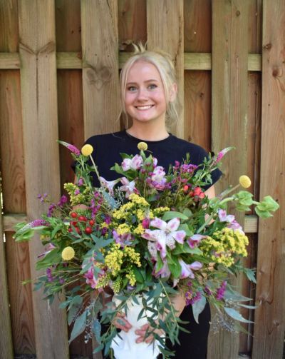 Smiling woman holding a large bouquet of colorful flowers.