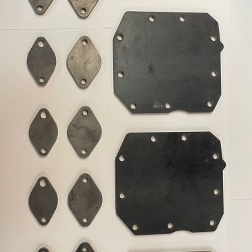 Various metal and rubber parts with holes laid out on a white surface.