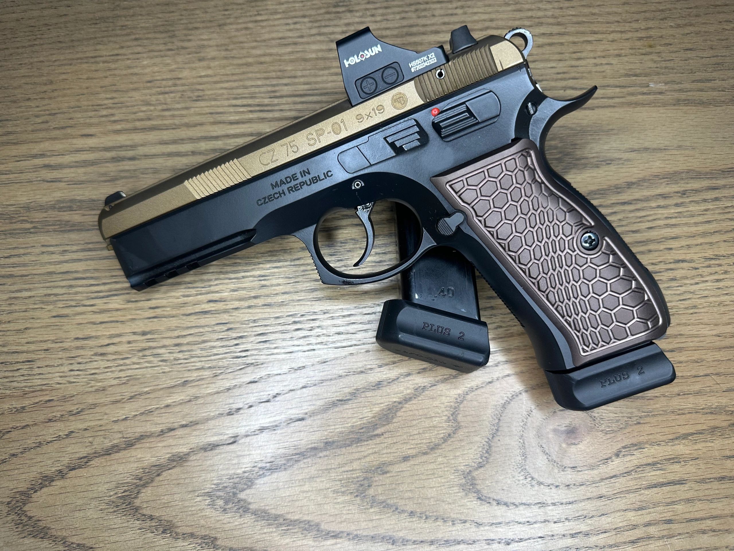 CZ 75 SP-01 pistol with honeycomb grip pattern on a wooden surface.