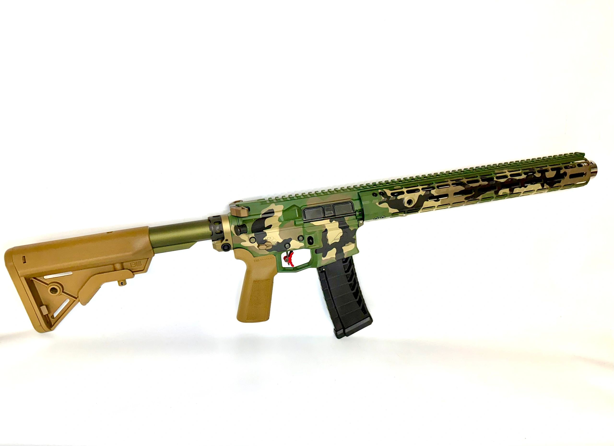 Camouflage-patterned rifle with tan stock and grip on white background.