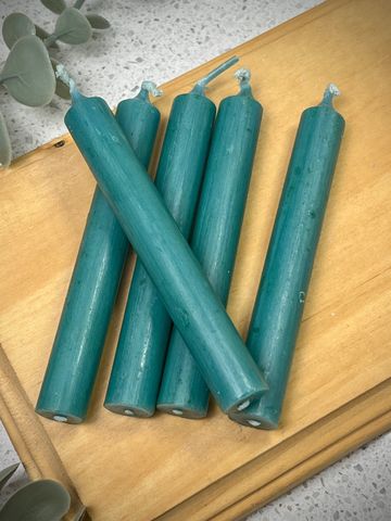 Five teal taper candles arranged on a wooden surface.