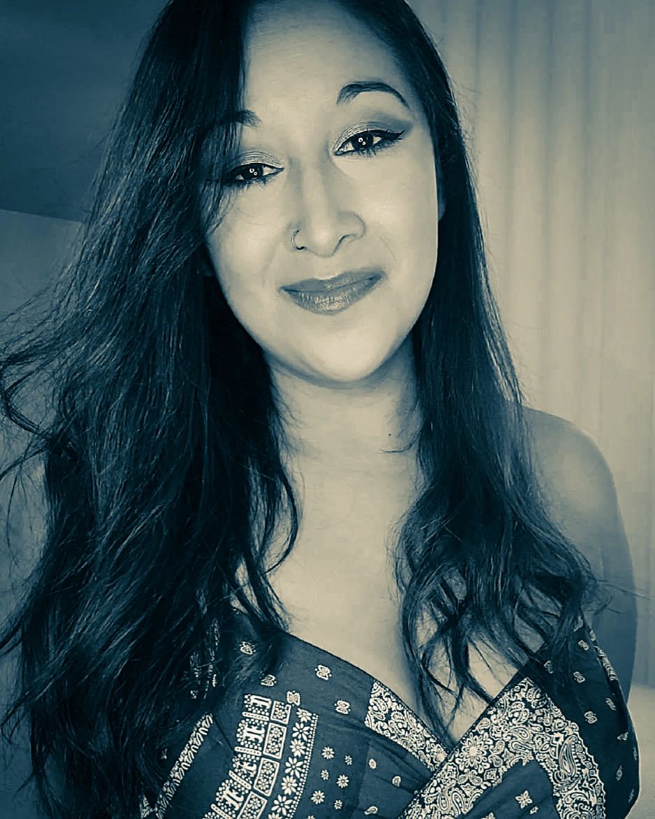 Smiling woman with long dark hair and patterned top.