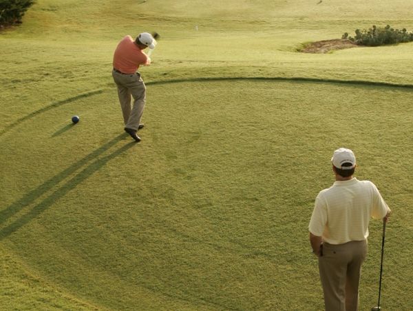 Two men playing golf on a sunny course.
