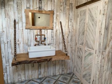 White sink on the wooden counter with a square mirror hanging above it.
