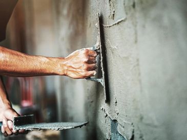closeup hand of cement plaster worker on wall for house building
