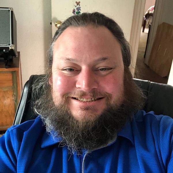 Smiling man with a beard wearing a blue shirt.