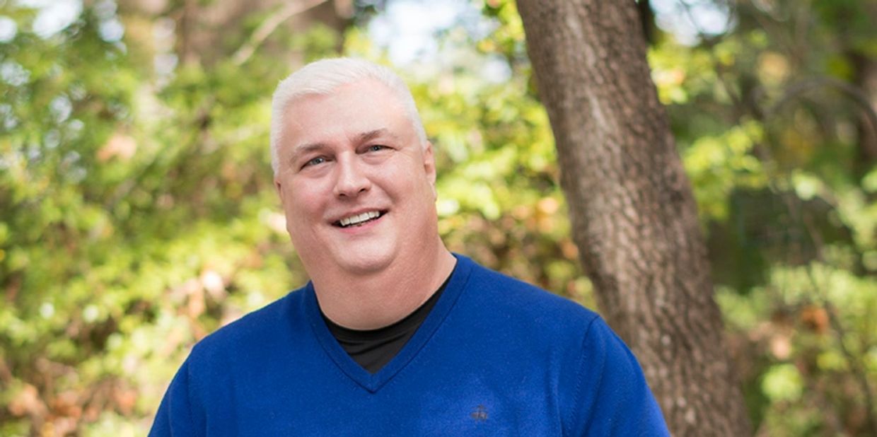 Smiling man with white hair outdoors.