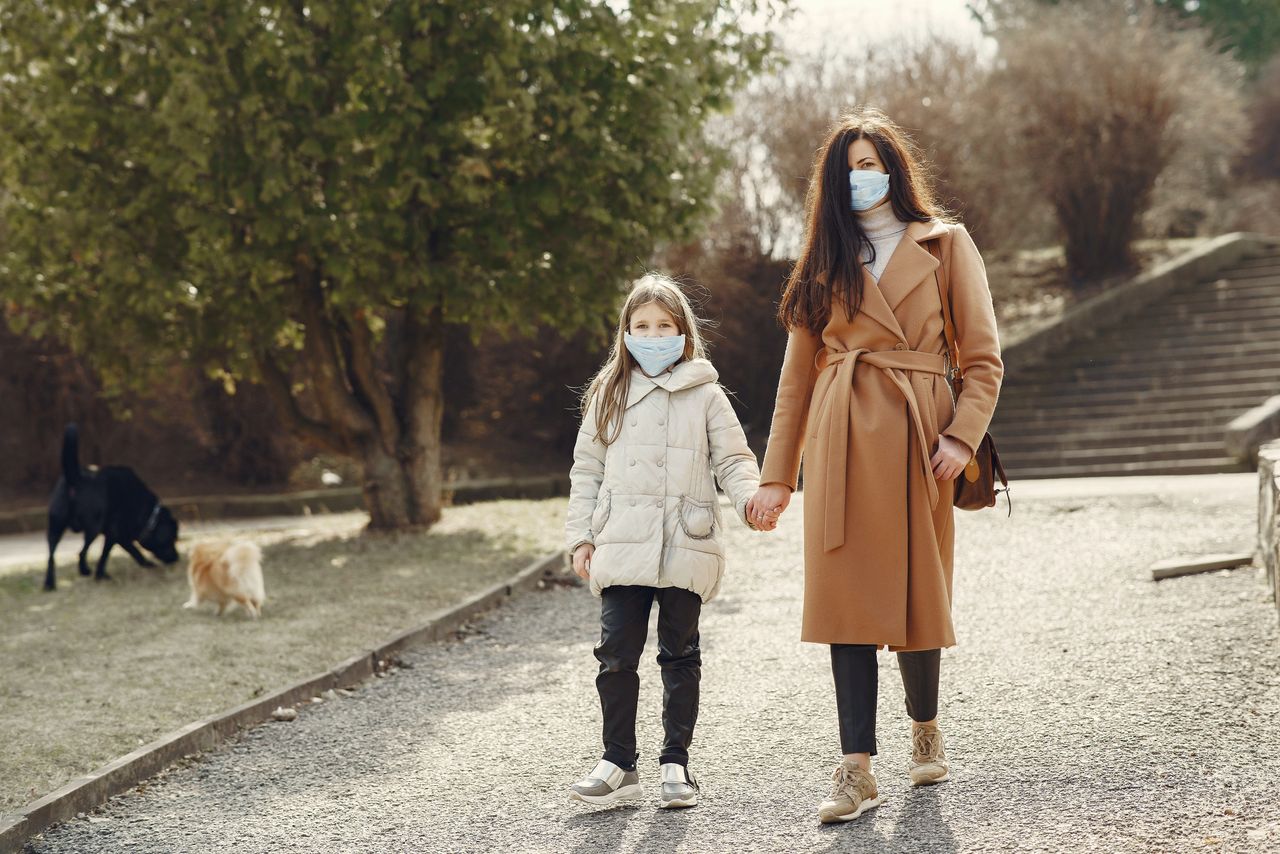 girl and mum walking in park wearing face masks