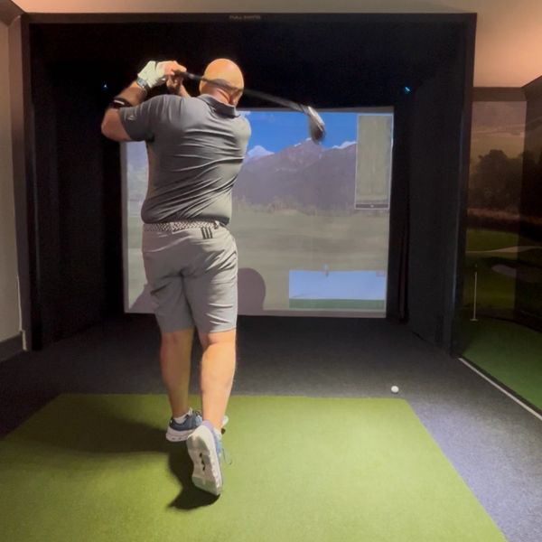 Man playing golf in an indoor golf simulator room.