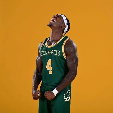 Basketball player in Saint Leo uniform celebrating passionately.
