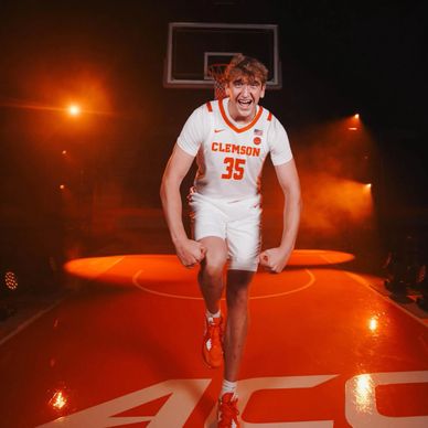 Clemson basketball player flexing on court with intense expression.