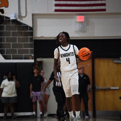 Basketball player in white Knights jersey holding a ball on court.