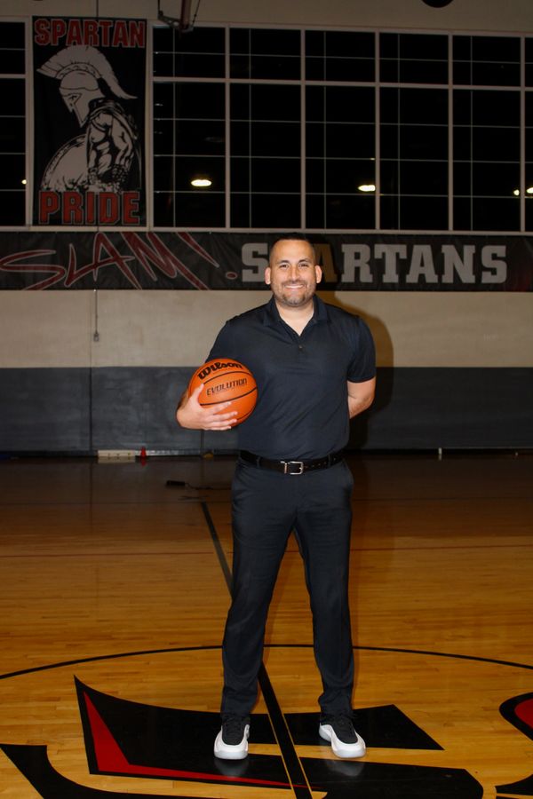 Man holding a basketball in a gym with Spartan Pride banners.