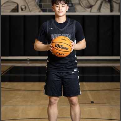 Young basketball player posing with a basketball on the court.