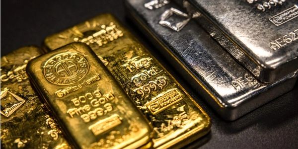 Gold and silver bars stacked together on a dark surface.