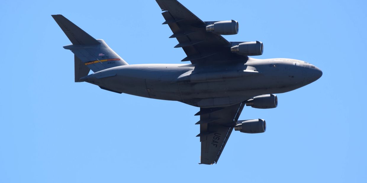 US Air Force cargo plane flying against a clear blue sky.