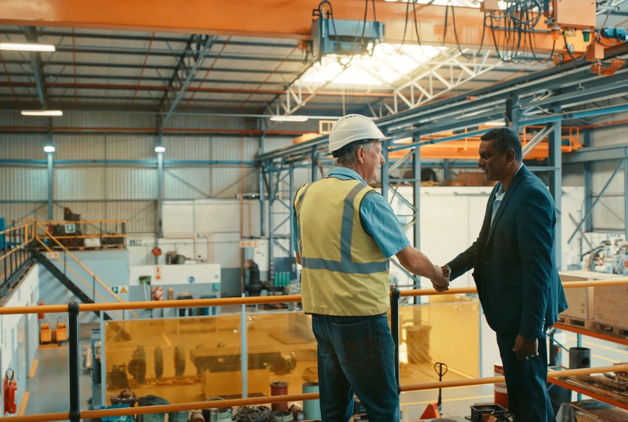 Operational leader shakes hands with high performing team member in a manufacturing facility