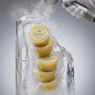 Dr. Kim's Mosquito Butter containers frozen in ice with a spray mist.