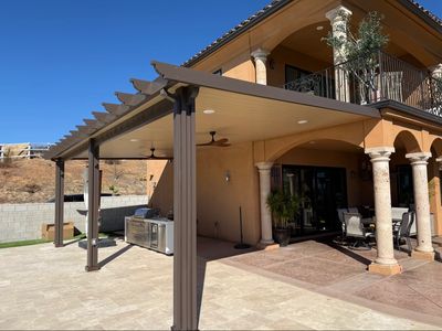 Modern patio cover attached to a large house with outdoor kitchen.