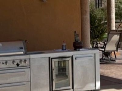 Outdoor kitchen setup with grill and refrigerator.
