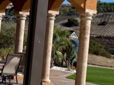 Outdoor patio area with columns and lawn.