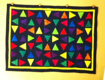 Colorful triangular patterns on a black fabric wall hanging.