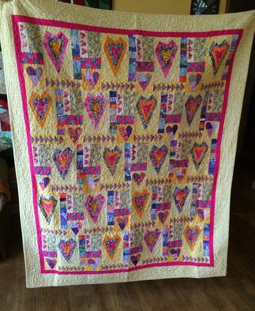 Colorful handmade quilt with heart designs and patchwork patterns.