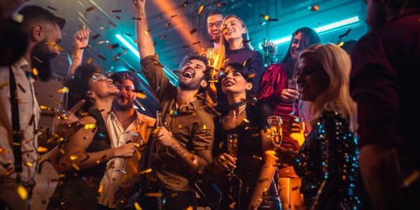 Group of friends celebrating and dancing at a lively party with confetti.