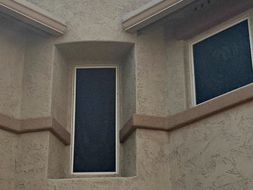 Two large windows on a beige stucco wall.