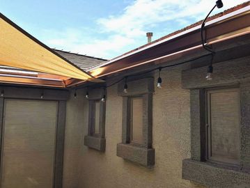 Beige stucco exterior with windows and outdoor lights.