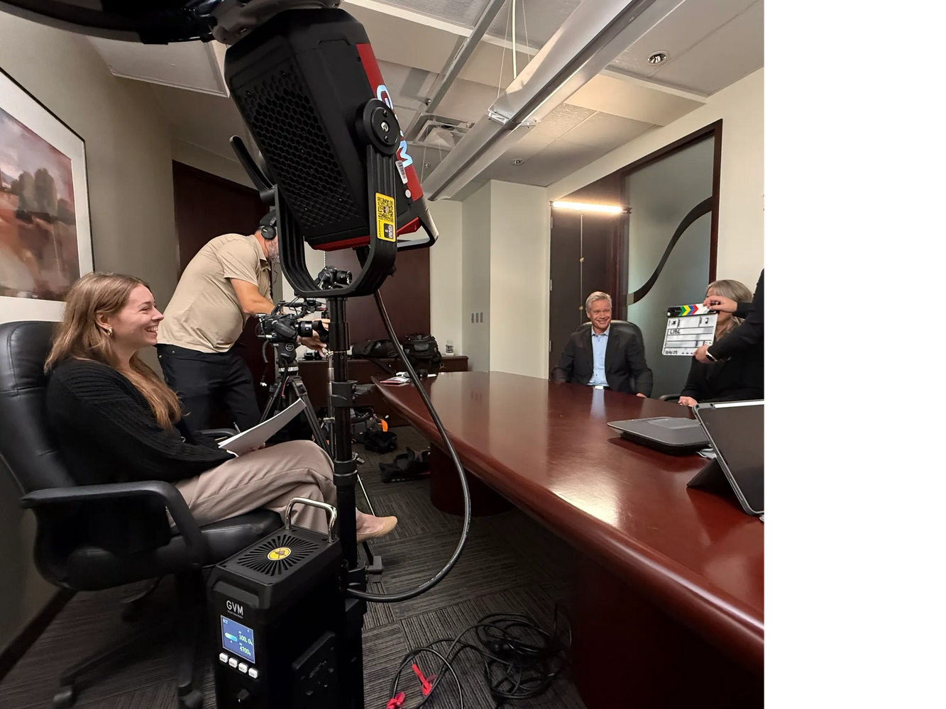 Image of Samantha McNeil interviewing clients during a video shoot, surrounded by equipment. 