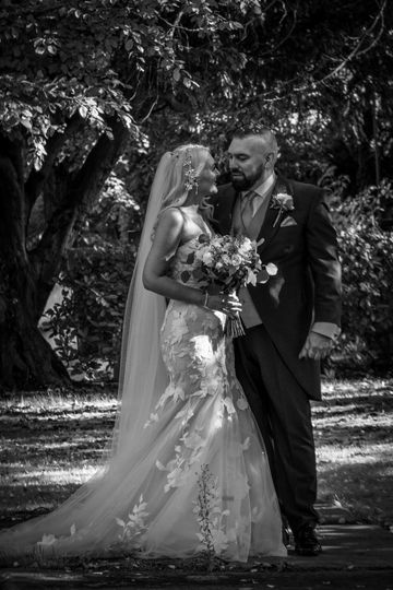 Black and white photo of a bride and groom sharing a moment outdoors.