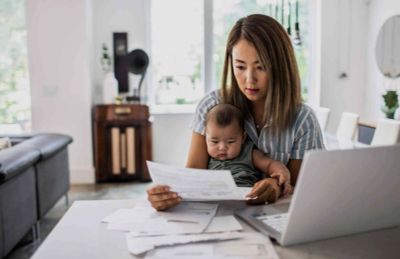 Woman with baby reviewing bills at home.
