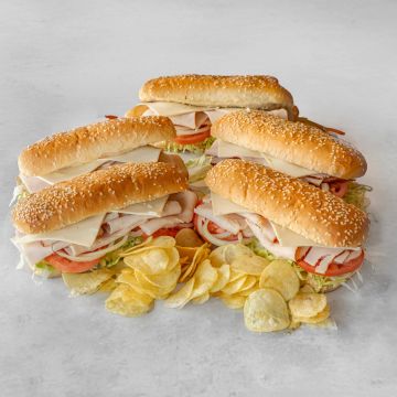 Four turkey sandwiches with potato chips.