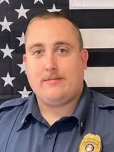 Portrait of a uniformed police officer in front of an American flag.