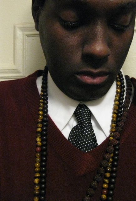 Picture of Moorish Brooklyn in white shirt, blue tie with white spots, sweater and mala beads.
