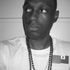 Black and white picture of Moorish Brooklyn, white t-shirt, mala beads, chain and two flag pins.
