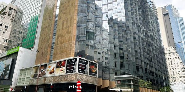 Modern urban buildings with reflective glass facades in a city setting.