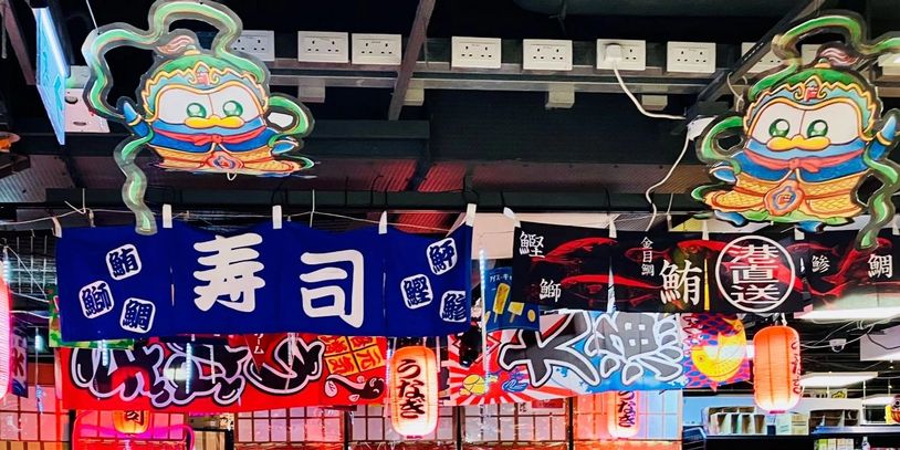 Colorful Japanese sushi restaurant banners and lanterns hanging indoors.
