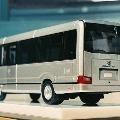 A detailed model of a Toyota Coaster bus displayed on a platform.