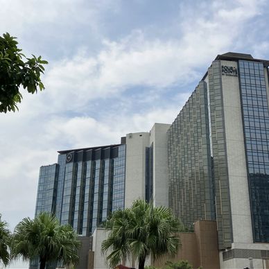 Modern glass and concrete office buildings stand tall under a partly cloudy sky.