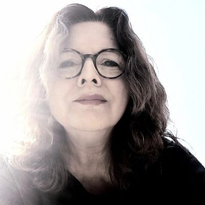 Retrato de mujer con gafas y cabello rizado.