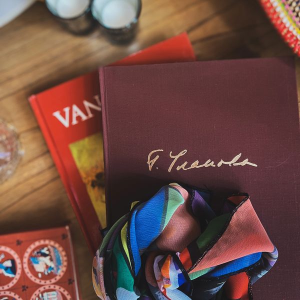 Colorful scarf on a stack of books with a wood table background.