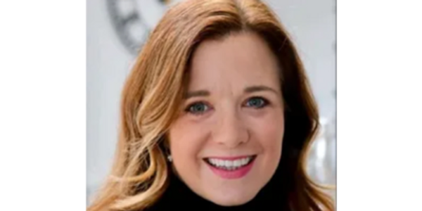Smiling woman with light brown hair and blue eyes, wearing a black top.
