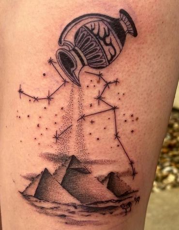 Tattoo of an Aquarius symbol pouring stars over pyramids.