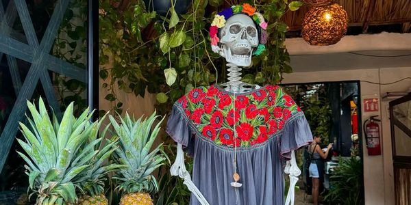 Calavera vestida con flores y rodeada de piñas.